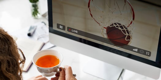 woman with tea at deskptop monitor watching basketball live stream